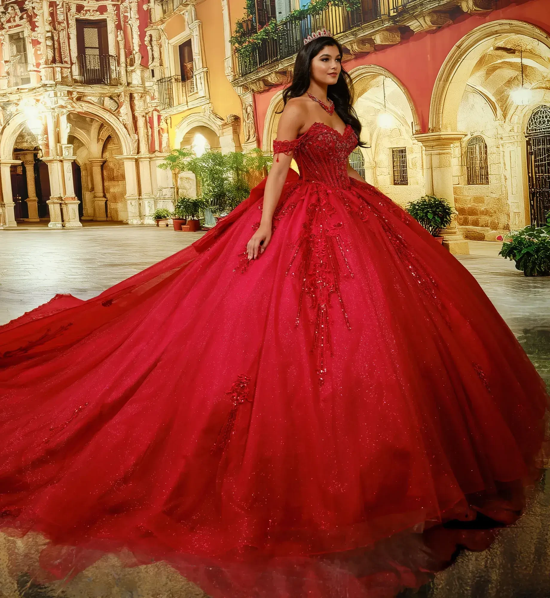 A woman wearing a large, ornate red gown with a long train, standing in an elegant outdoor setting featuring historic architecture.
